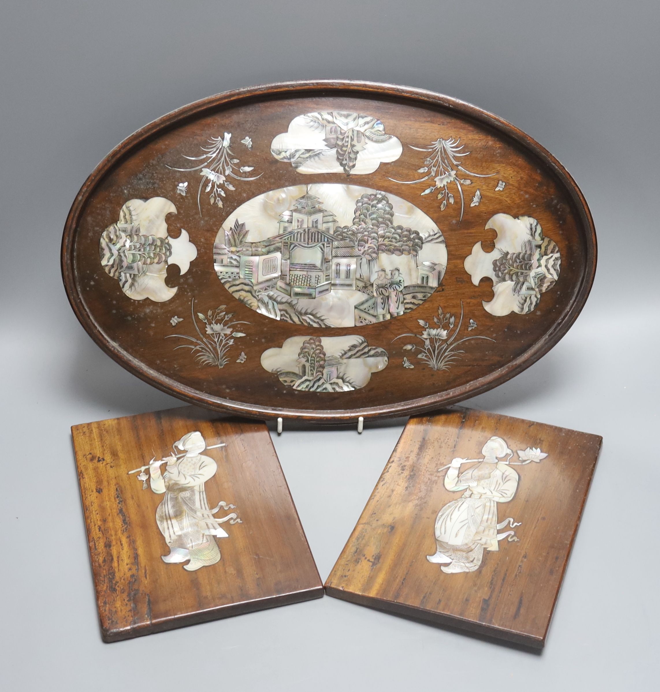 A Chinese hardwood and mother of pearl inlaid oval tray, 43cm and a similar pair of panels decorated with figures